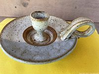 Angled front view of the candle holder showing the speckled glaze and loop handle.