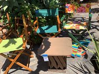 Full set of 6 directors chairs and small wood chair, showing different upholstery and finishes placed outdoors in sunlight.