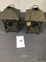 Pair of metal candle holders shown from front, displaying tree and star cut-out patterns.