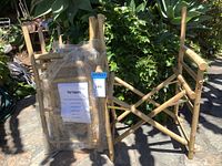 Five bamboo director's chairs stacked outdoors with protective plastic wrap and a label from Pier 1 Imports attached.