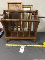 Solid wood magazine rack with turned spindle sides and measurement tape showing approximate size
