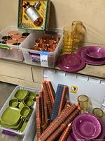 Wide view showing copper cups, yellow plastic cups, fuchsia melamine dinnerware, placemats tubes