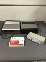 Overview of Pentax portable video cassette recorder and tuner with Betacor tapes and additional device captured on black surface