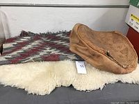 Photo of sheepskin rug, woven leather rug partially visible, and the leather pouf resting on top.