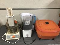 Lot of small kitchen appliances including Black & Decker food processor, West Bend Poppery II popcorn popper, GE deep fryer, and Brita pitcher.