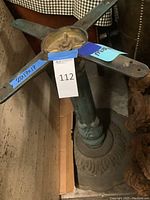 Close-up of cast iron table base showing green patina and decorative details under the tabletop.