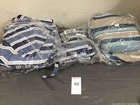 Six umbrella covers wrapped in plastic with blue and white stripes, laid horizontally.