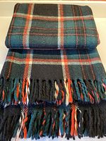 Folded view of wool blanket showing checkered pattern and fringed edge with multiple colors