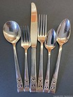 Cutlery pieces including spoons and forks displayed to show detailed coronation pattern handles.