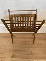 Front view of mid-century wooden folding magazine rack showing slatted sides and cutout back panel
