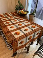 Table runner draped over a table showing colors and texture with plants and fruit bowl on top