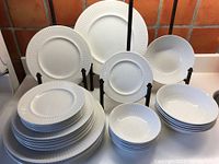 Full arrangement of all plates and bowls in the lot displayed on table with stands.