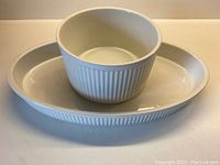 Oval and round white ribbed ceramic casserole dishes from Johnson Bros. ATHENA series stacked for size comparison.