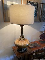 Full view of the mid-century ceramic drip table lamp with cream linen shade, showing overall shape, color, and placement on wooden table.