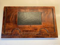 Top view of the rectangular maple cheeseboard with black slate insert centered and surrounding wood with carved grooves.