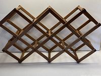 Full view of the vintage wooden folding wine rack showing wooden slats and intersections where bottles are stored.