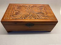 Top view showing hand carved leafy foliage design on the hinged lid with original aged brass latch.