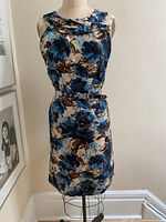 Front view of the sleeveless dress on a dress form showing the floral print and silhouette.