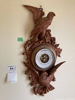 Full view of the wood carved barometer with two bird figures and decorative floral elements, mounted on a wall.