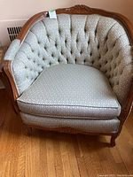 Front-facing photo of the tufted armchair showing curved shape and upholstery pattern