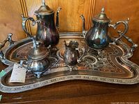 Full view of the coffee and tea service on the intricately decorated silverplated tray, showing all five pieces including coffee pot, teapot, creamer, sugar bowl, and tray.