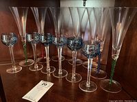 Full set of 10 stemware pieces arranged in a wooden cabinet, 5 flutes with colored twisted stems and 5 blue cut-glass goblets.
