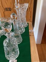 Photo showing two decanters with round faceted stoppers and two crystal vases with cut patterns on table