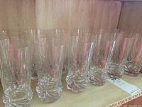 Set of 12 clear crystal drinking glasses arranged in two rows showing the vertical line cuts and thick sculpted bases.