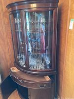 Full frontal view of curved curio cabinet showing glass display doors and lower wood cabinet