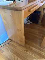 Side view of solid wood desk showing wooden side panel and leg construction.