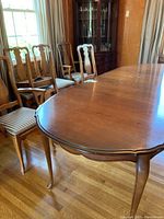 Dining table with chairs arranged around it, showing polished wood surface and chair design