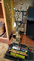 Photo showing brass fireplace tools on stand and black metal log carrier with Chimney logs in front