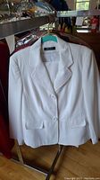 White tailored jacket by Arvida hanging on rack