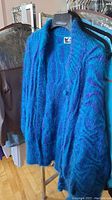 Blue and black fuzzy patterned jacket hanging on rack