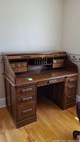Front view of wood roll-top desk showing top and bottom drawers