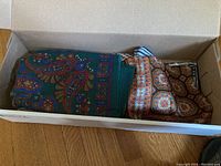 Box with green paisley and brown paisley scarves folded inside