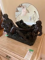 Front angle showing two seated female figures in bronze tone with a round mirror attached at base.