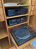 Full view of wooden shelving unit containing Sony CD player, Sony duo cassette deck, and Dual CS 530 turntable on pull-out bottom shelf.