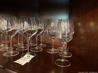 Crystal stemware displayed on a wooden shelf. Clear glasses with long stems arranged in rows.