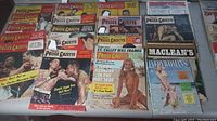 Photo showing multiple National Police Gazette magazines arranged in rows with prominent boxing cover images and a few other magazines like Maclean's and Everybody's