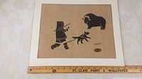 Full view of the Inuit print on bulap measuring 13.25 x 13.25 inches with ruler for scale.
