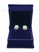 Pair of oval greenish-blue opal earrings with topaz accents in royal blue velvet box.