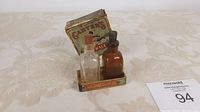 Lot contents showing clear and amber glass bottles with corks in metal tray and original box