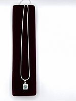 Full view of necklace displayed on red velvet cushion