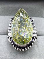 Close-up front view of the pear-shaped golden rutilated quartz set in detailed 925 silver ring.