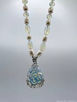 Necklace showing alternating moonstone and pearl beads with carved moonstone pendant featuring silver rose design mount.