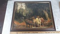 Framed oil painting showing a wooded scene with multiple cattle and background figures of a herdsman on horseback and another standing man.