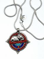 Front view of the silver pendant showing the sleeping cat and colorful inlays of turquoise, lapis, and red coral.