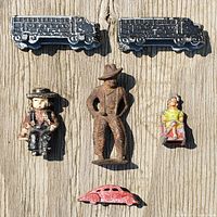 Top view of the six cast iron toys arranged on wooden surface, showing front details of figures and vehicles.