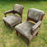 Photo showing the pair of antique Eastlake style ladies chairs set outdoors on grass, highlighting overall condition and upholstery.